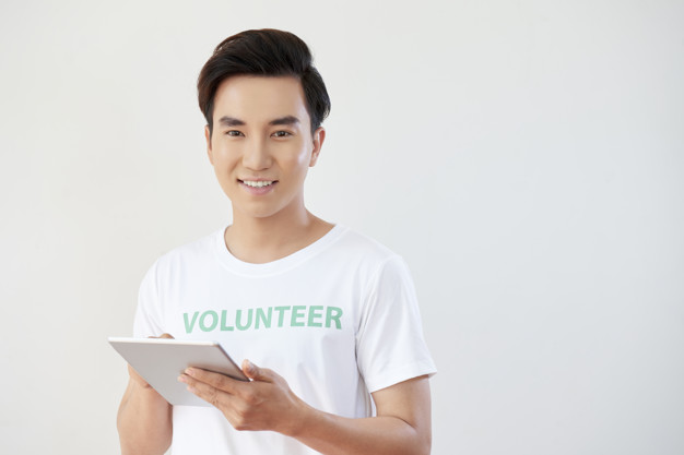 Volunteer working online Portrait of Asian young man working as volunteer and using digital tablet in his work isolated on white background